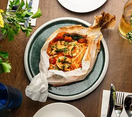 Artisanal linguine seafood pasta baked in parchment paper with rich tomato sauce